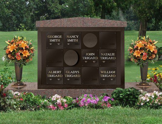 A granite columbarium with bronze niche plates carrying family names