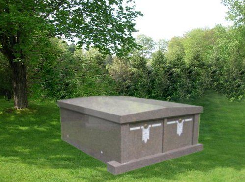 A granite crypt set on a lawn among trees