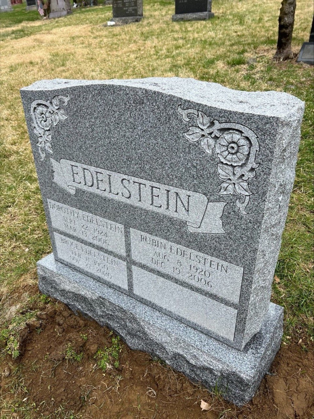 Grey granite upright with four family panels and carved scrollwork corners
