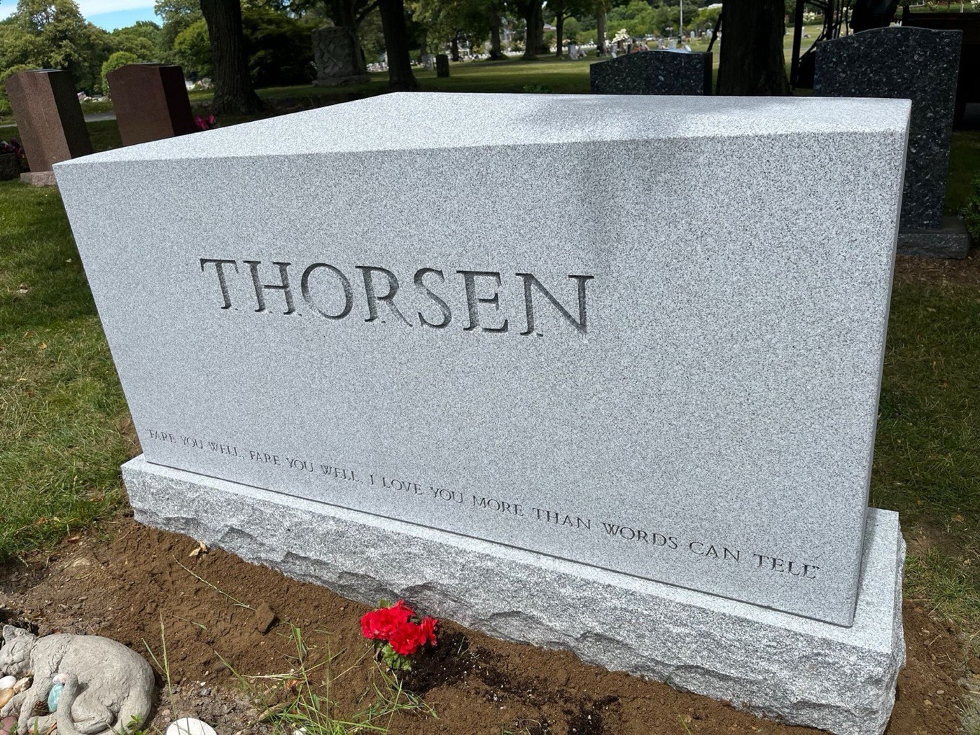 A large light grey granite monument lettered THORSEN, standing on a rock pitched base in a cemetery