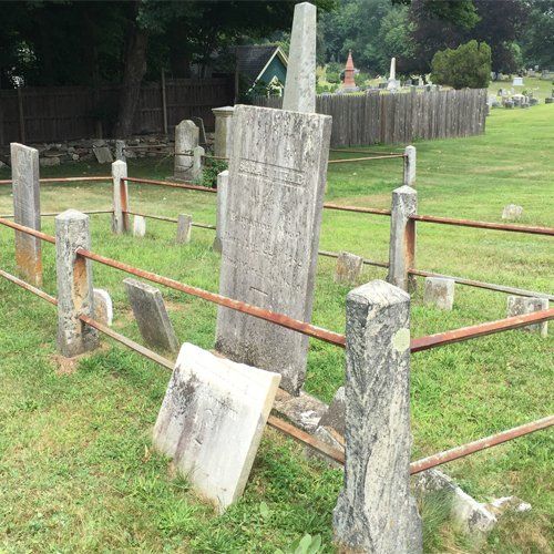 An old family plot with leaning and fallen marble headstones inside an iron rail